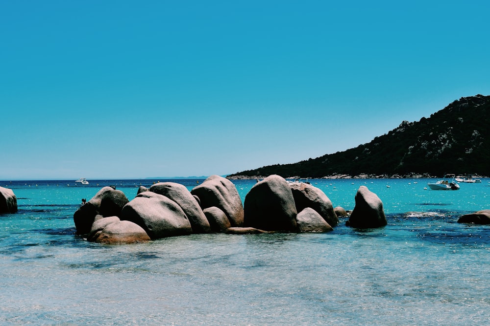 gray rocks on body of water under blue sky during daytime