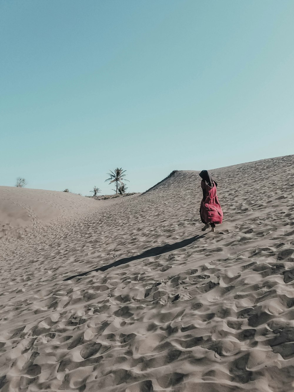 woman in red dress walking on sand during daytime