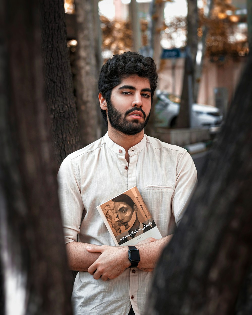 man in white dress shirt holding brown book