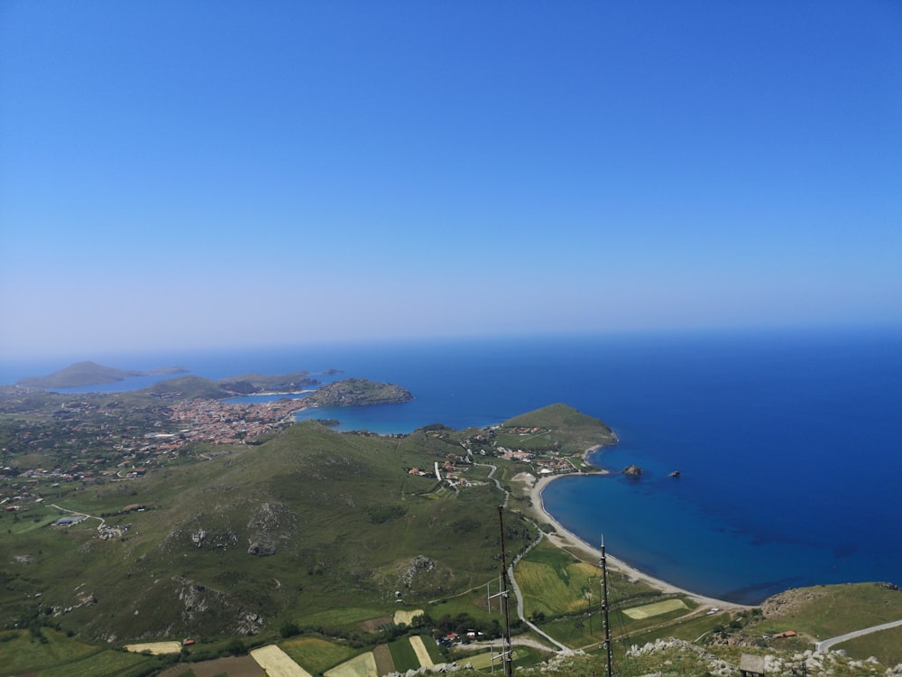 green grass field near blue sea under blue sky during daytime