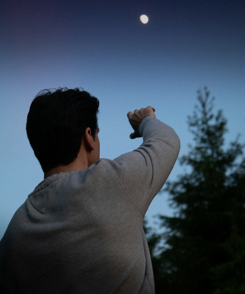 man in gray long sleeve shirt raising his right hand