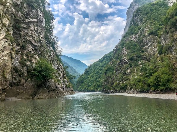رودی سبزرنگ میان دیواره‌های بلند سنگی و کوه‌های جنگلی