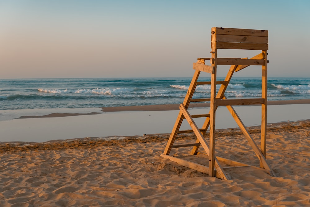 chaise de sauveteur en bois marron sur la plage pendant la journée