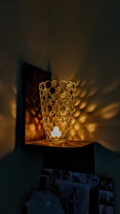 Colorful 3D printed decorative vase displayed on a cozy wooden shelf with warm lighting.
