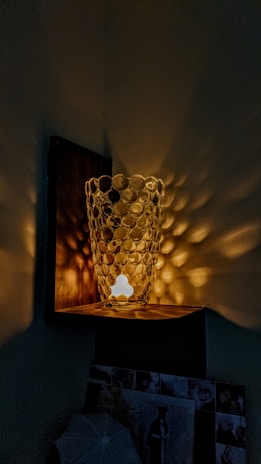 An elegant 3D-printed vase with intricate patterns sitting on a wooden shelf.