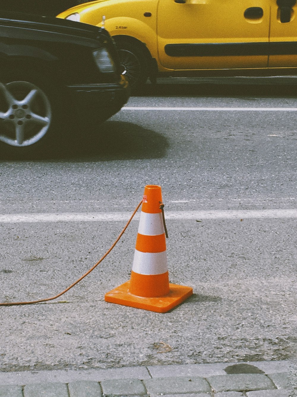 orange and white traffic cone on gray asphalt road