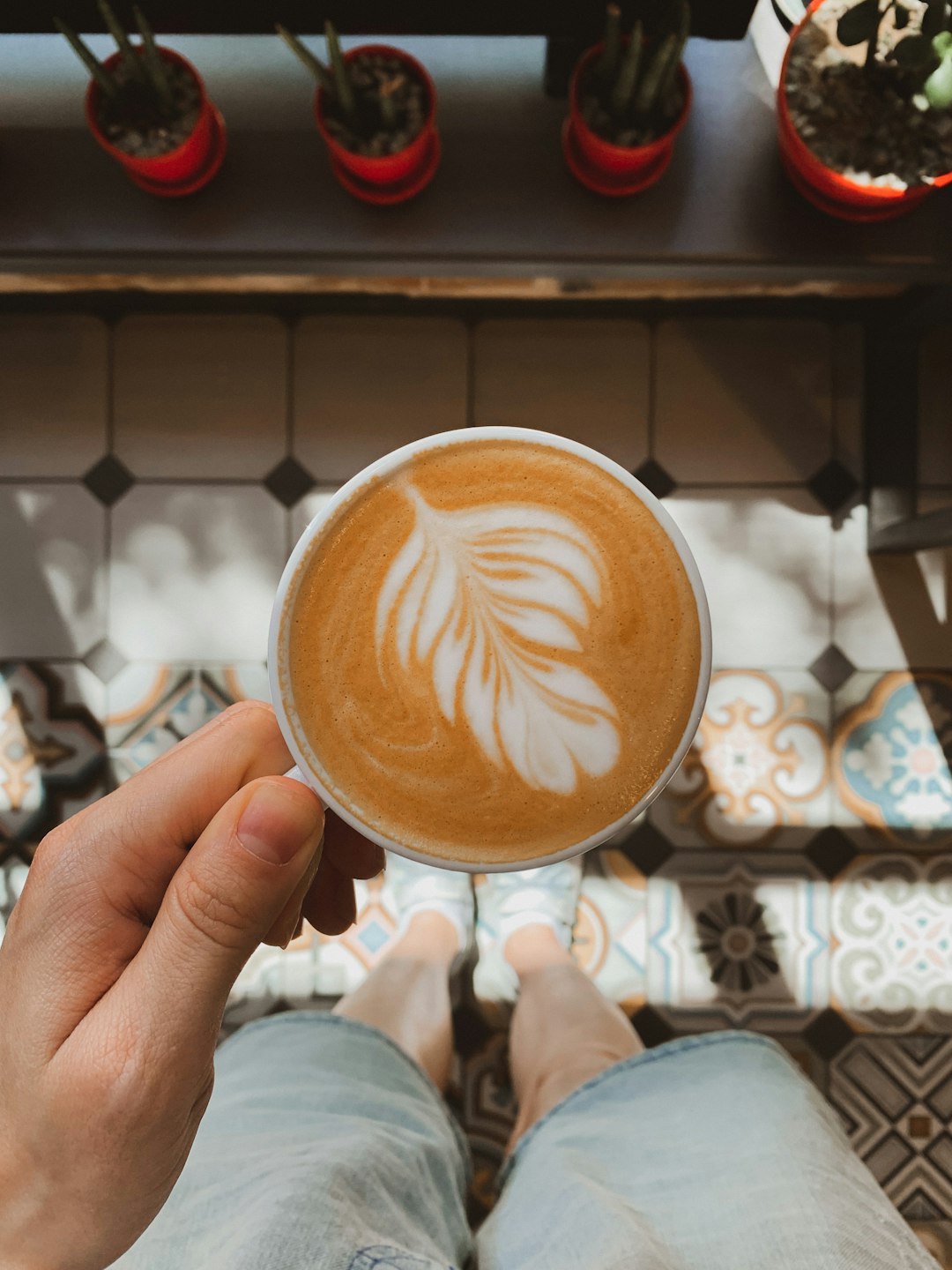 person holding white ceramic mug with brown liquid