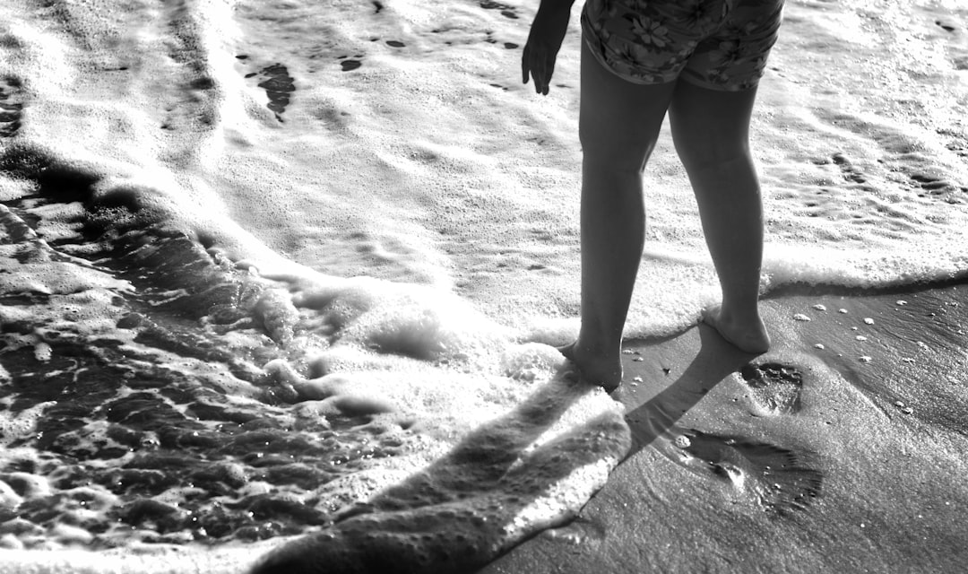 person in black and white shorts walking on white sand during daytime