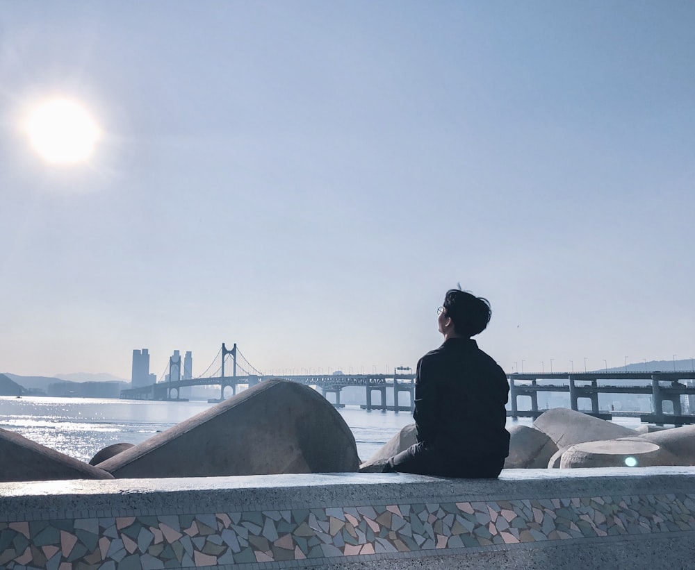 man in black jacket sitting on white bench