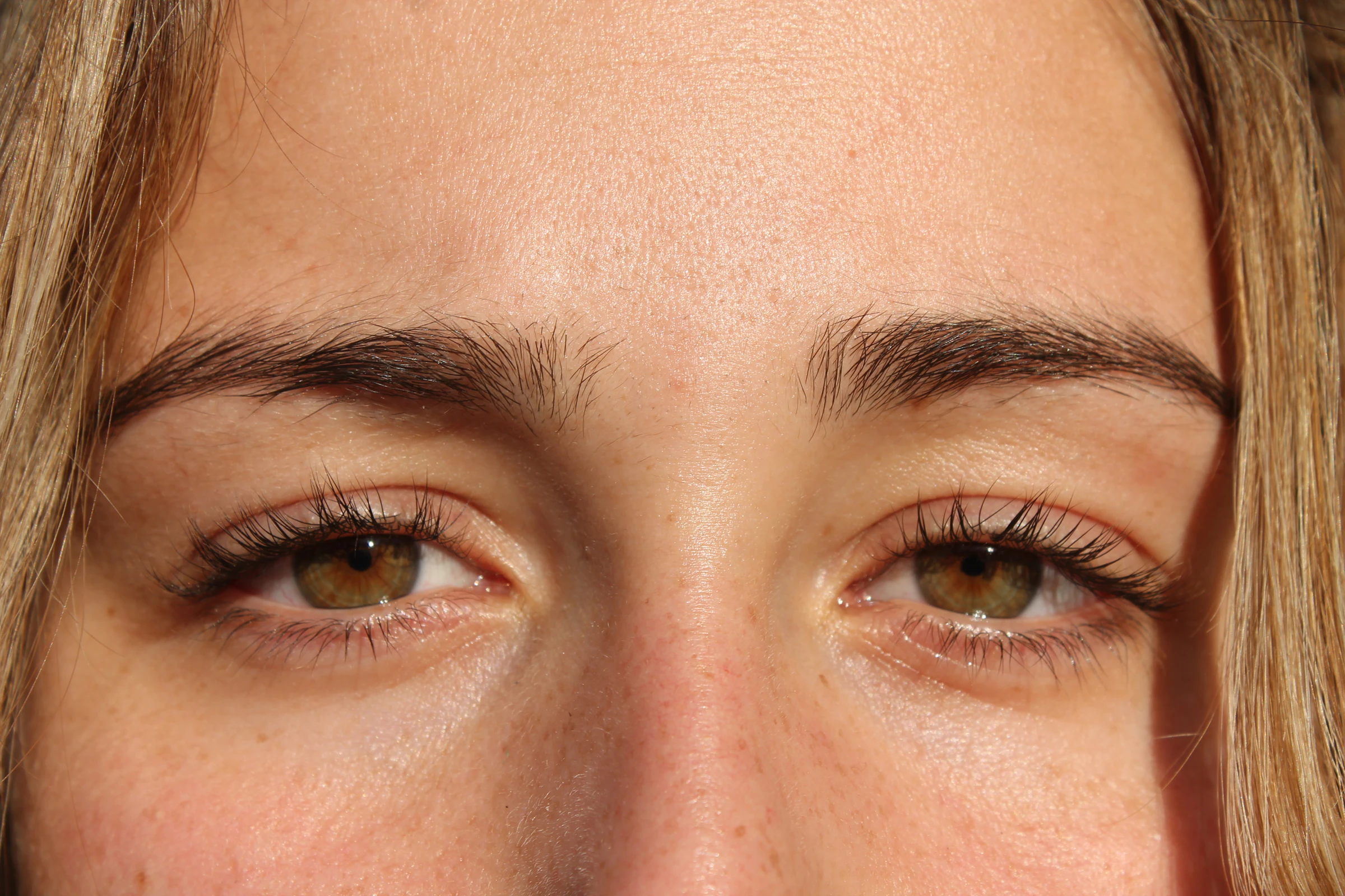 A close-up frontal portrait shows both eyes, eyelashes and naturally full, shaped eyebrows.