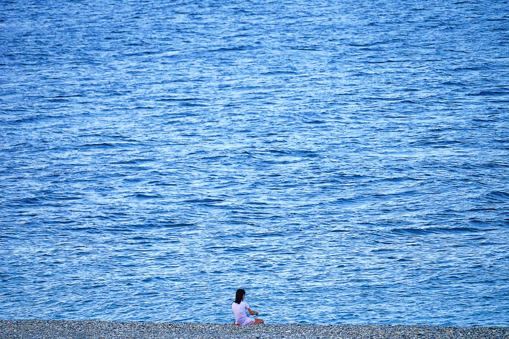 2 women sitting on beach shore during daytime