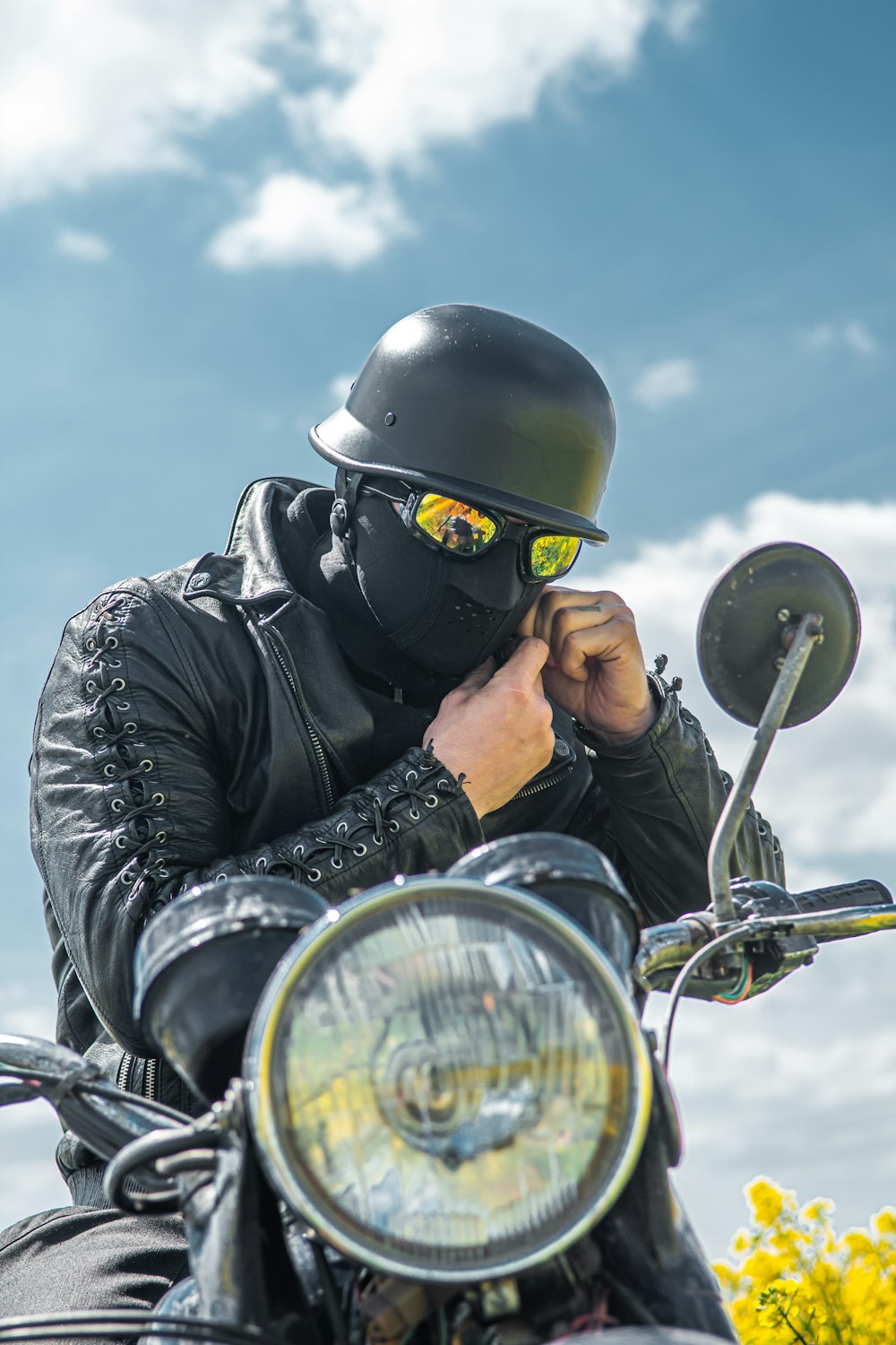 man in black leather jacket wearing black helmet riding on motorcycle during daytime