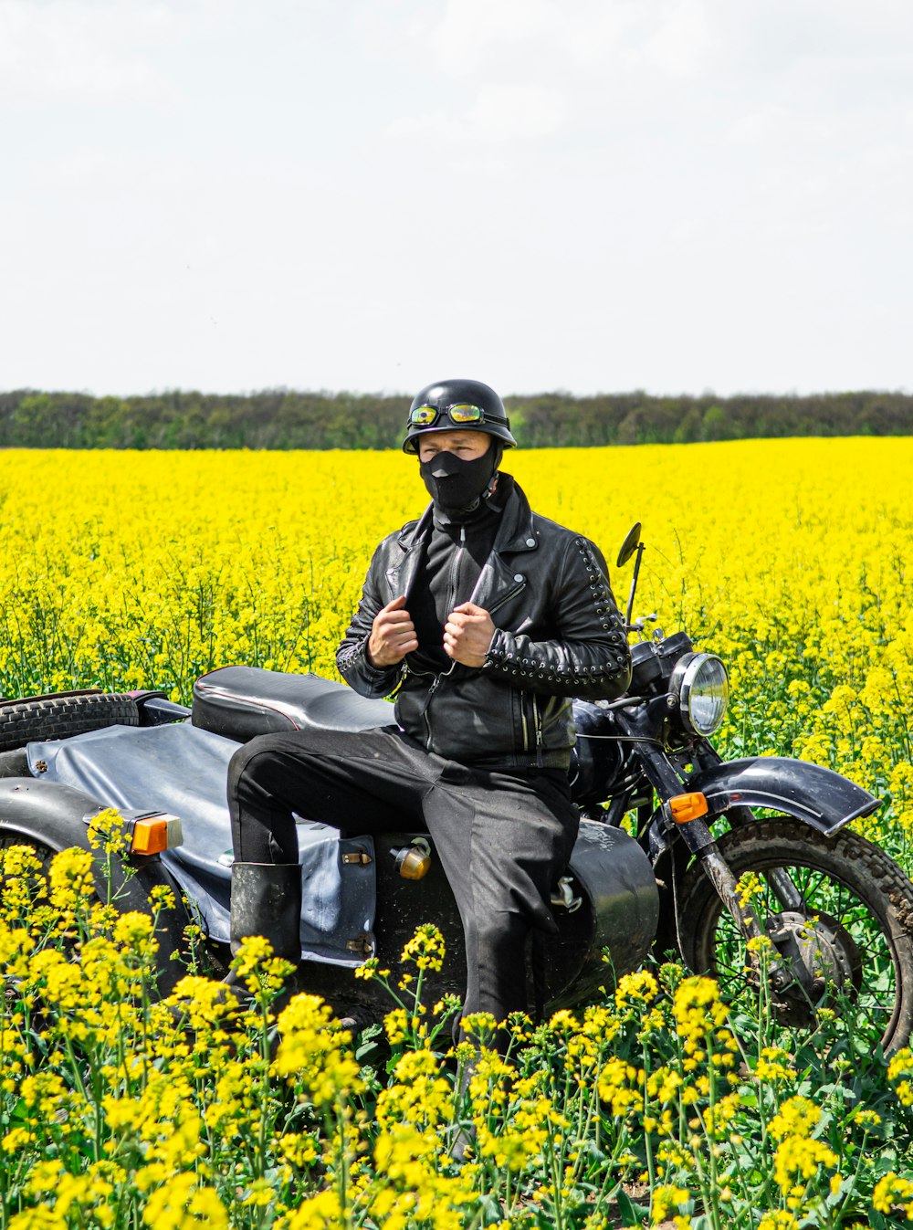 man in black jacket riding motorcycle on yellow flower field during daytime