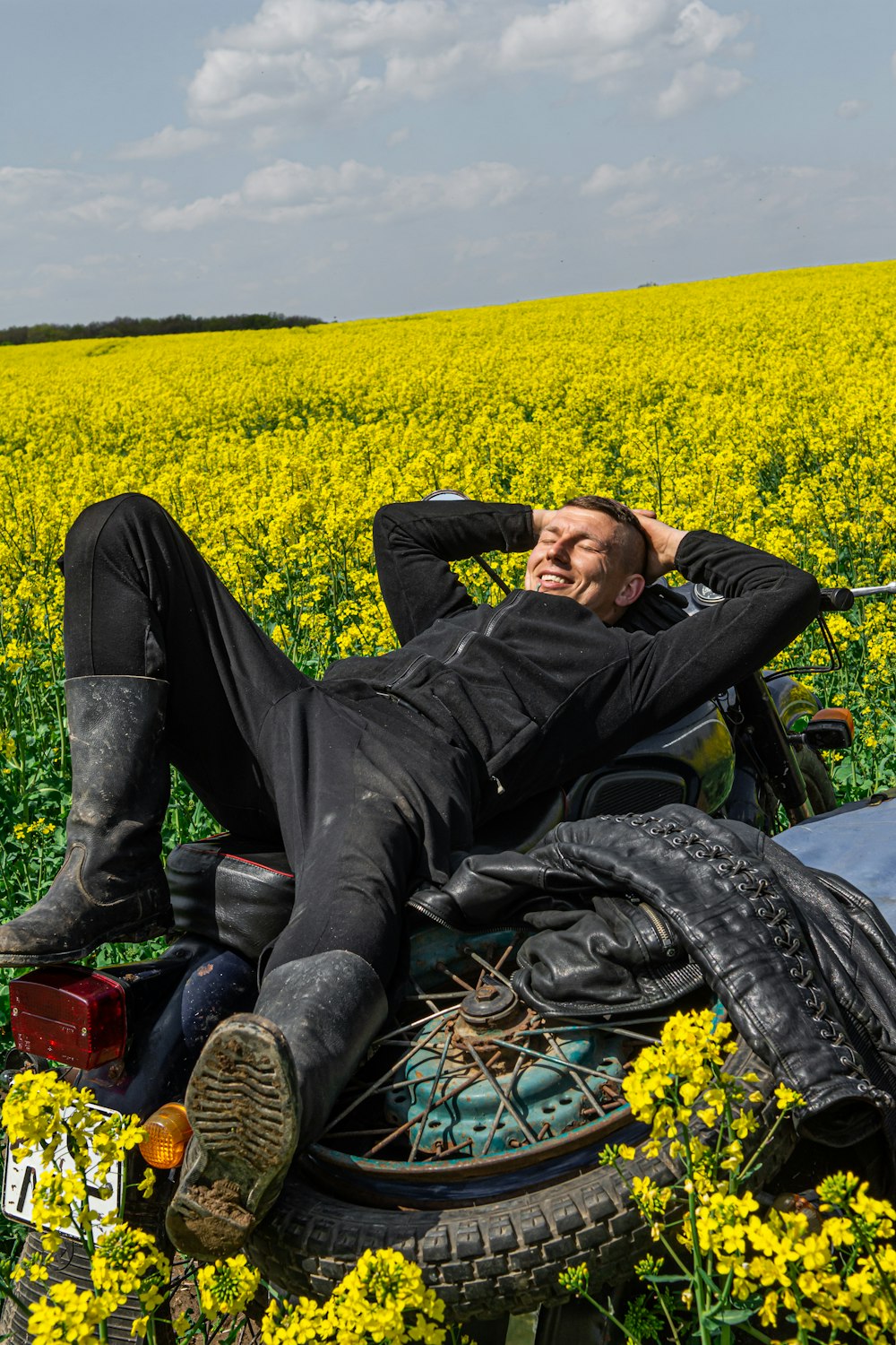 man in black jacket lying on yellow flower field
