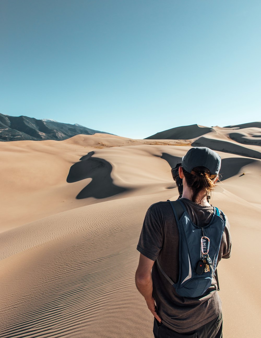 man in black t-shirt and black backpack standing on sand