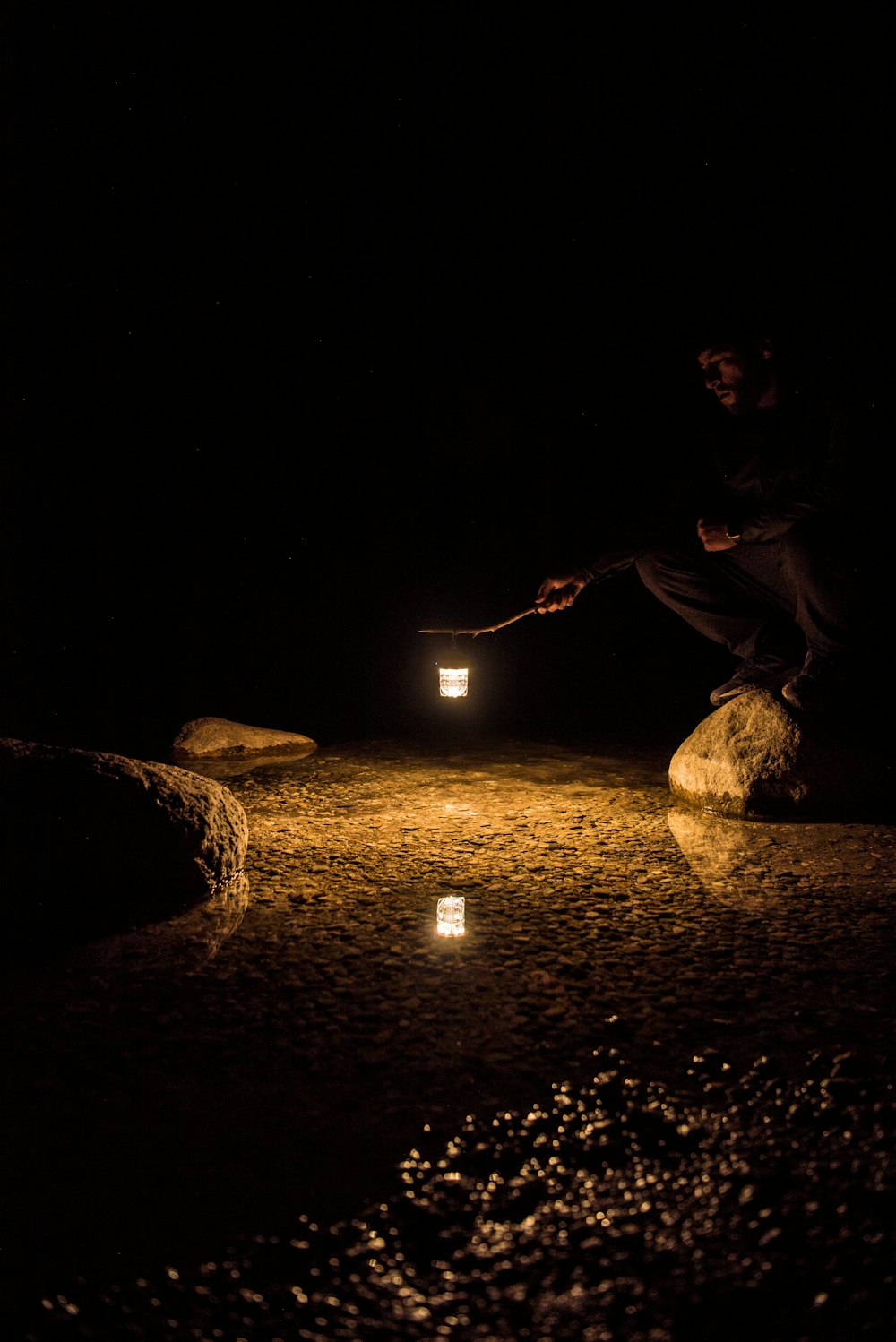 man in black shirt sitting on rock during night time