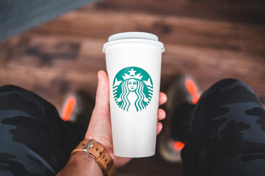 person holding white and green starbucks disposable cup
