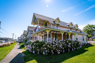 A peaceful homestead featuring a wraparound porch and blooming flower beds.