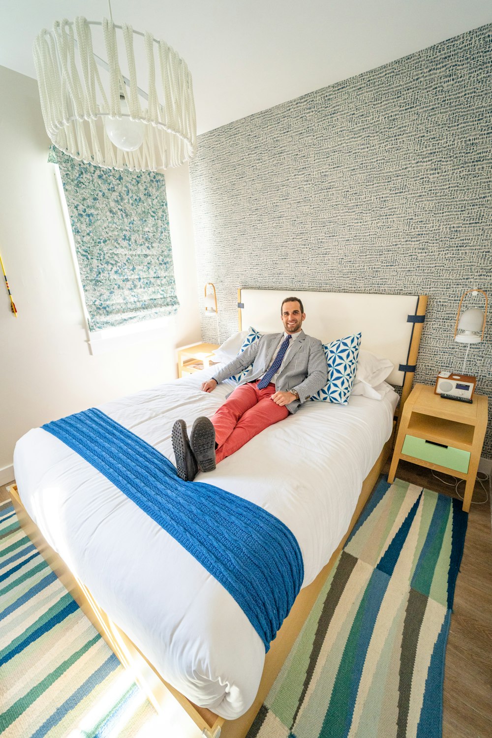 man in white and blue stripe dress shirt sitting on white bed