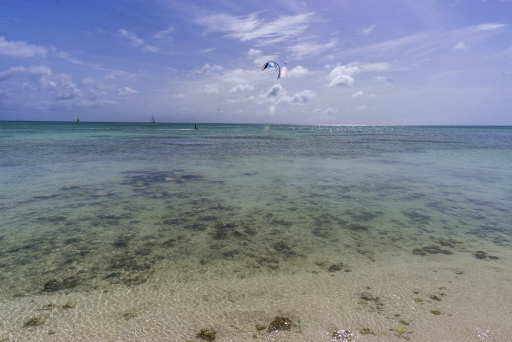 person in blue and green wetsuit surfing on blue sea under blue sky during daytime