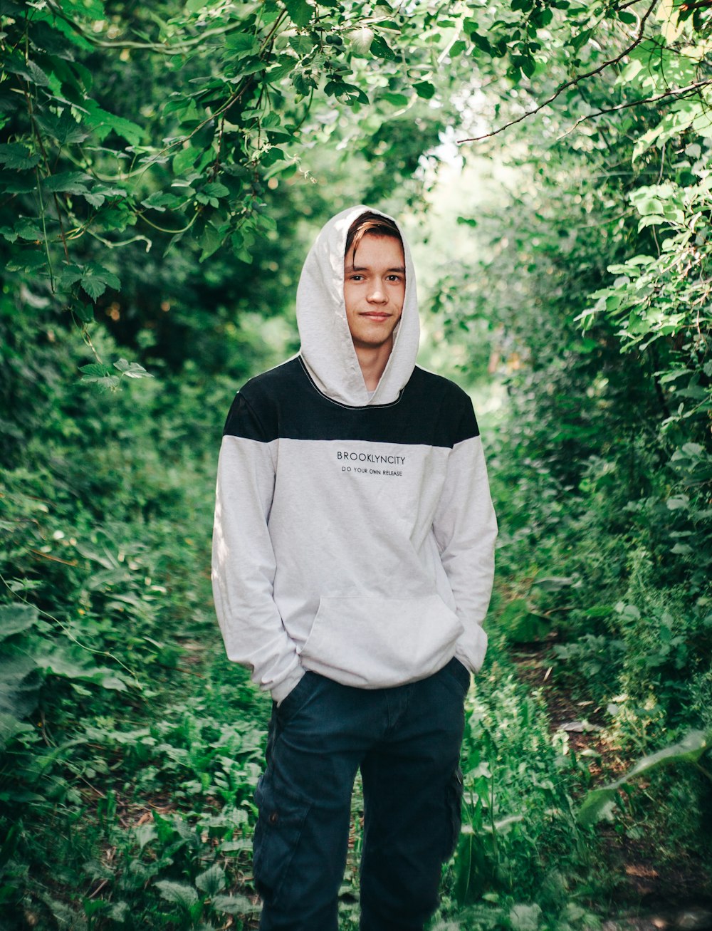 man in gray hoodie standing in forest during daytime