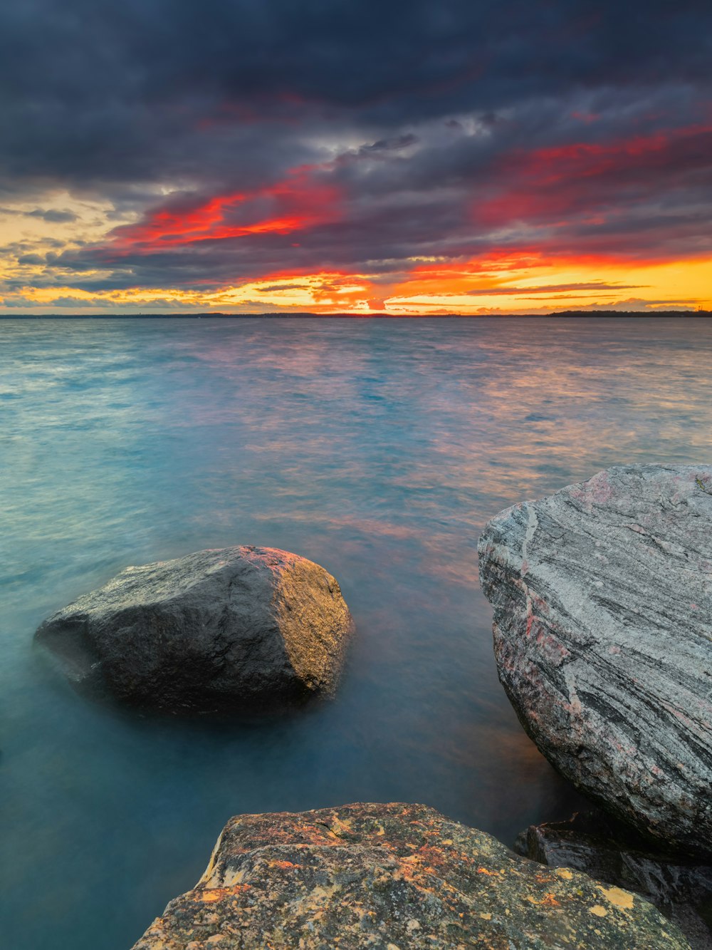 gray rock formation beside body of water during sunset