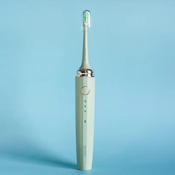 Close-up of a sleek electric toothbrush with soft bristles glowing under warm light