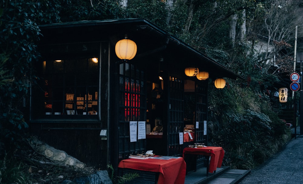 woman in black jacket sitting on red chair near brown wooden table during night time