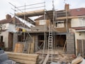Photo of residential house under construction with workers and scaffolding.