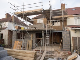 Photo of residential house under construction with workers and scaffolding.