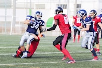 football players in red jersey shirt and red pants running on green grass field during daytime