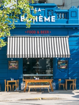 brown wooden chairs and tables near blue wooden building during daytime