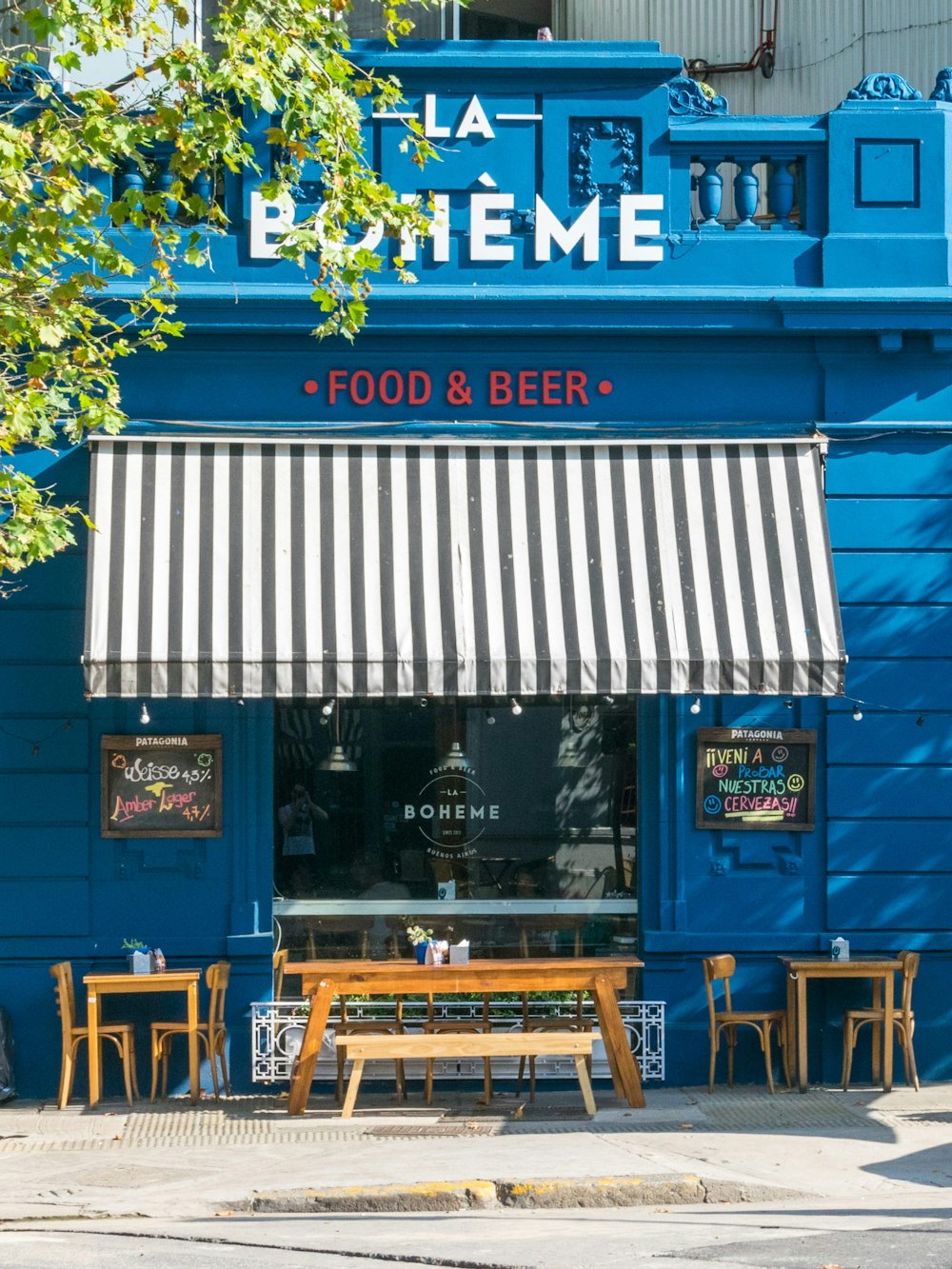 brown wooden chairs and tables near blue wooden building during daytime