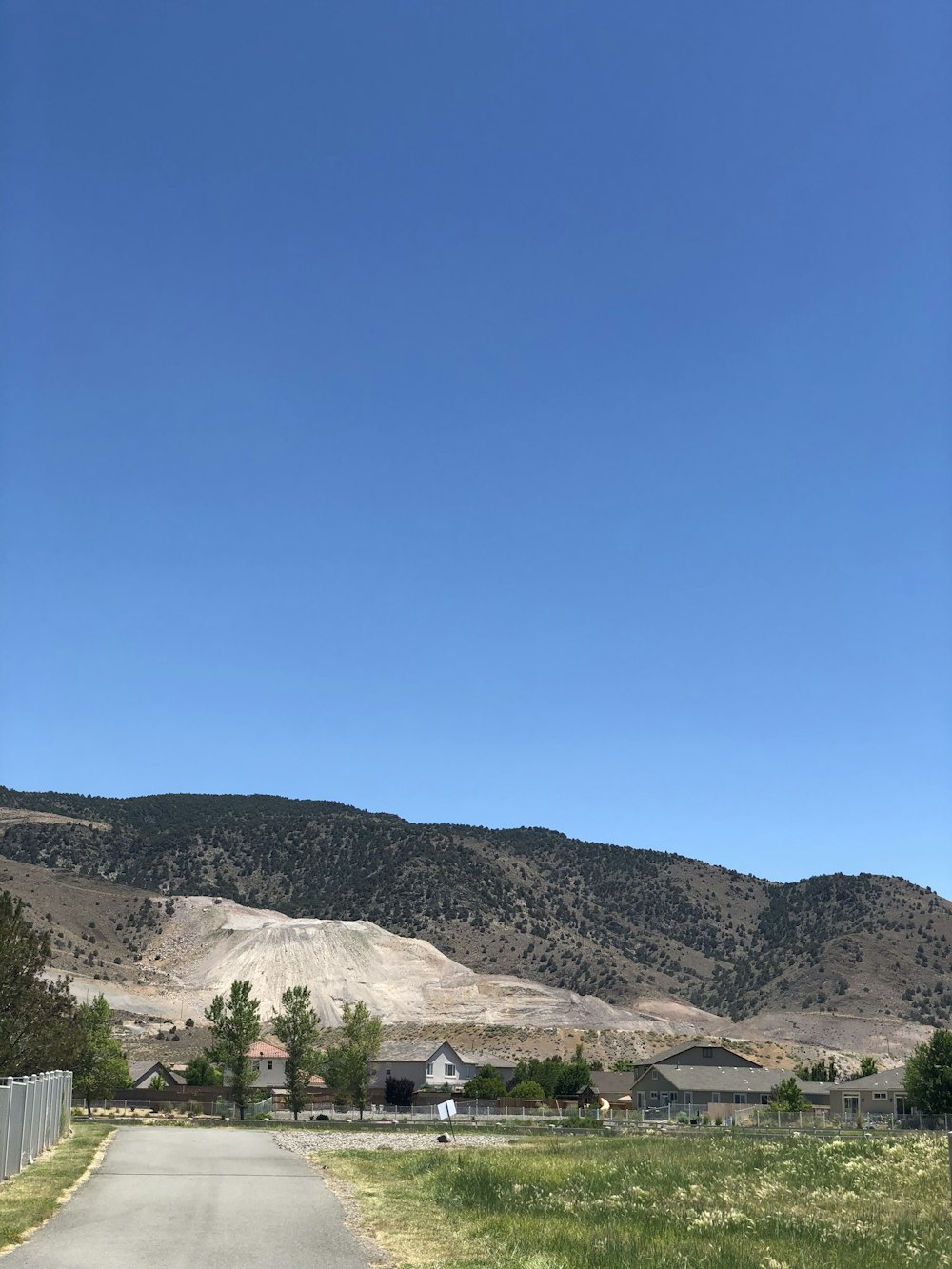 green grass field near brown mountain under blue sky during daytime