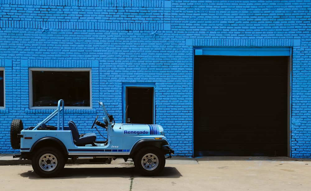 white and black jeep wrangler parked beside blue building