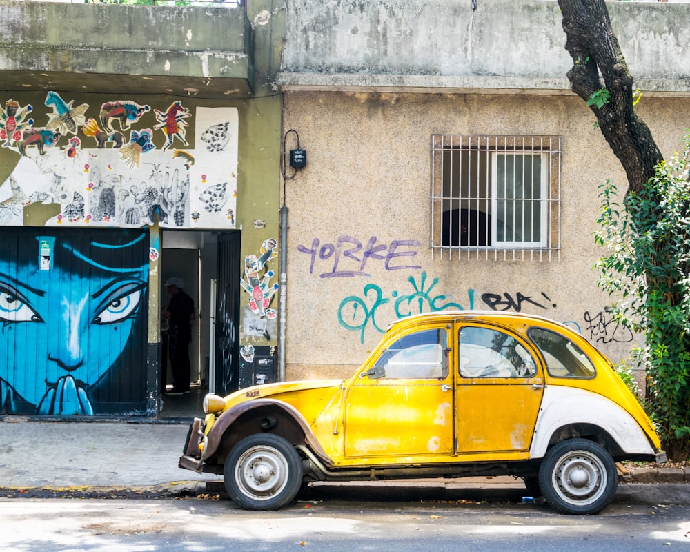 yellow volkswagen beetle parked beside white concrete building during daytime