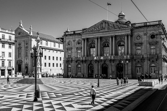 grayscale photo of person walking on pedestrian lane near building in City Hall Portugal