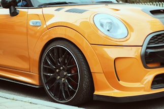 A sleek orange and black themed contact section with a phone and WhatsApp icon next to a car image