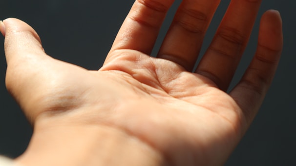 A close-up of a hand being examined with palm lines visible under natural light.