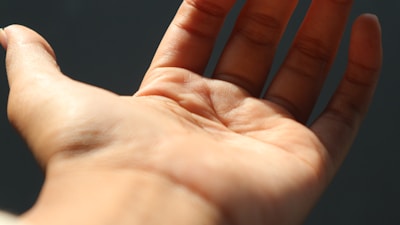 Close-up of a hand with detailed palm lines highlighted, set on a warm dark yellow backdrop.