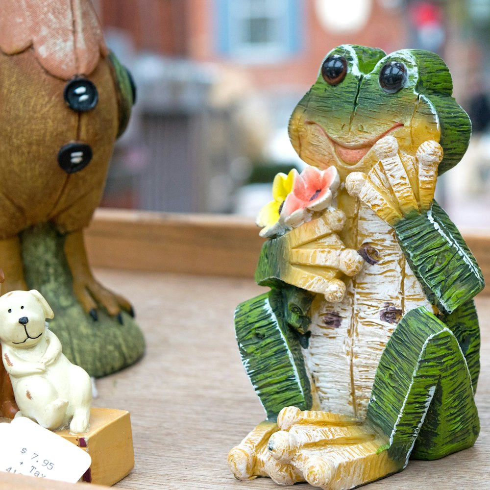 green frog holding book figurine