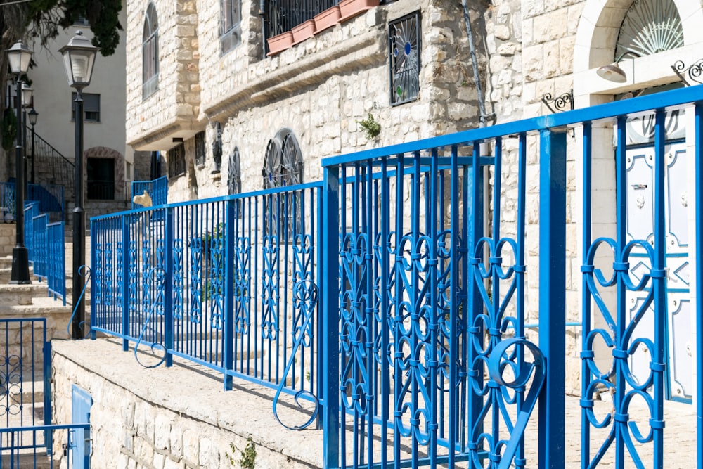 blue metal fence near white concrete building during daytime