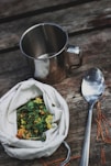 stainless steel spoon beside vegetable salad in stainless steel cup