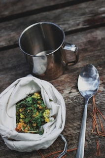 stainless steel spoon beside vegetable salad in stainless steel cup