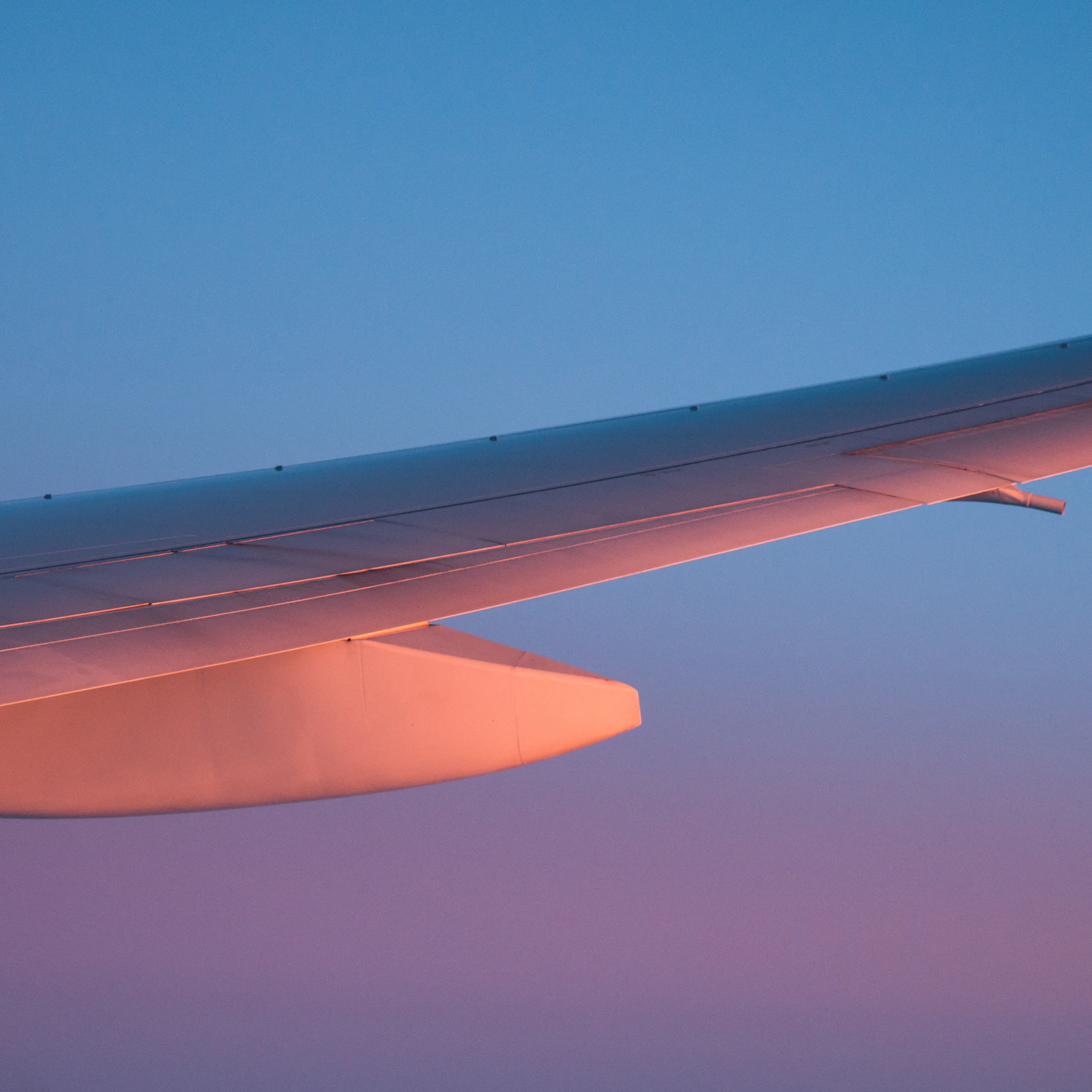 Aircraft wing above the clouds at golden hour