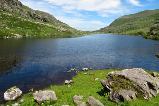 green grass field near lake during daytime in Gap of Dunloe Ireland