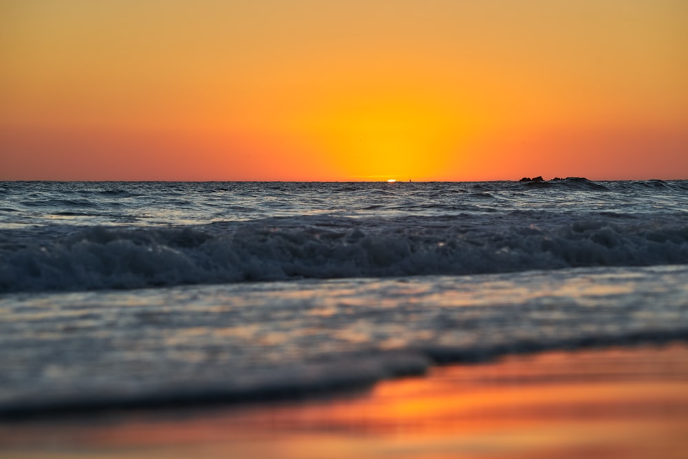 ocean waves crashing on shore during sunset