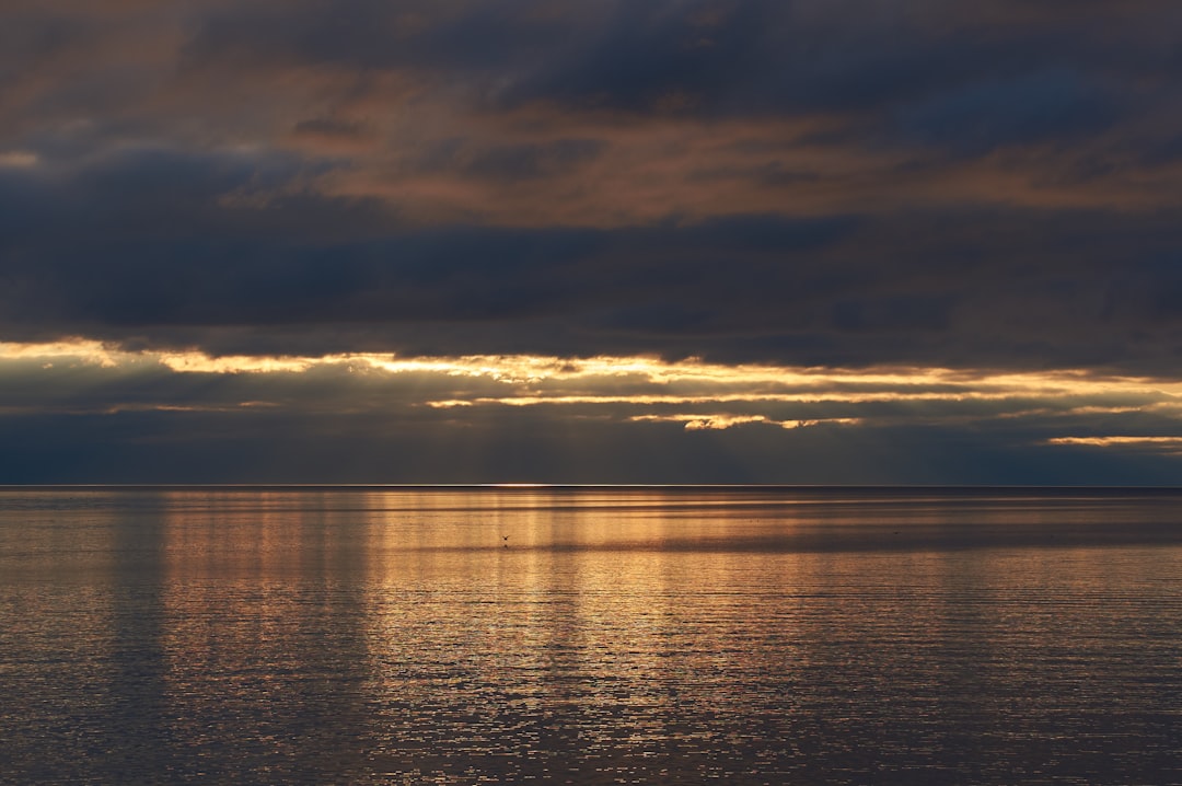 body of water under cloudy sky during sunset