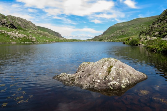gray rock formation on body of water during daytime in Gap of Dunloe Ireland