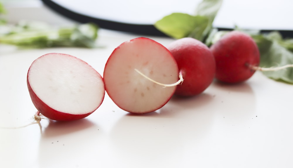 3 fruits ronds rouges sur assiette en céramique blanche